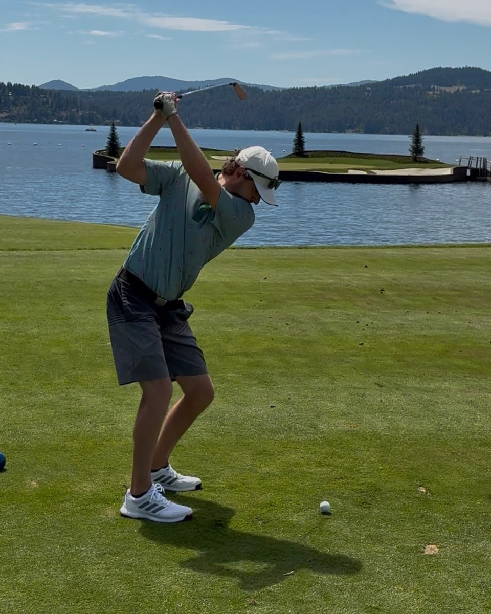Hayden Wehe swinging a golf club on a fairway beside a lake